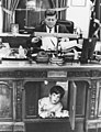Le président John F. Kennedy travaillant à son bureau alors que son fils joue à ses pieds en 1962.