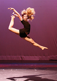 A contemporary dancer performs a stag split leap