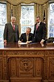 Georges W. Bush y signant une loi votée par le Congrès en septembre 2006. Sur le devant du bureau, le sceau présidentiel avec la tête de l'aigle tournée vers les flèches.