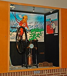 Installation dans une vitrine avec des appareils de plongée exposés devant deux cases extraites d'un album de Tintin.