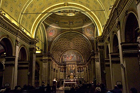 Image photographique d'une nef centrale voûtée en berceau avec arcs et colonnes sur les côtés, un dôme suspendu et au au fond le chœur et l'abside.
