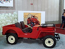 Photographie d'une voiture rouge exposée devant une vignette agrandie de l'album.