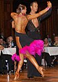Image 27Latin dancers in their costumes. The woman is wearing backless dress with deep slits on its lower portion, while the man is wearing a shirt with top buttons open. (from Fashion)