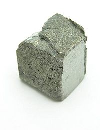立方体に近い形をした暗灰色金属片。表面は平坦でない。