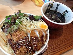 Tsukemen topped with fried pork cutlet, half of a soft-boiled egg and greens, in Singapore