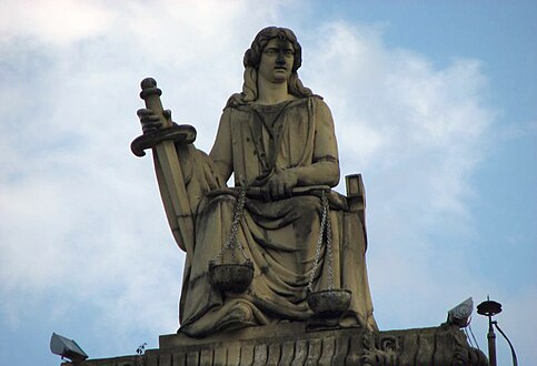 Escultura da justiça com sua balança e espada no topo do prédio.