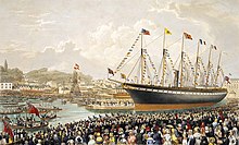 A crowd of people watch a large black and red ship with one funnel and five masts adorned with flags