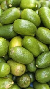 Fresh green lemons arranged closely together, with smooth textured peels and natural variations in size and color.